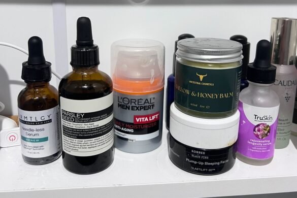Men’s grooming and skincare products including serums, moisturizer, and facial balm arranged on a bathroom shelf.